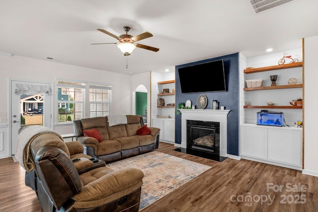 4040 Deep River Way, Waxhaw, NC 28173 - living area with ceiling fan, a fireplace with flush hearth, wood finished floors, and arched walkways