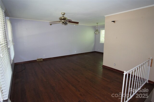 empty room featuring crown molding, visible vents, wood finished floors, baseboards, and ceiling fan