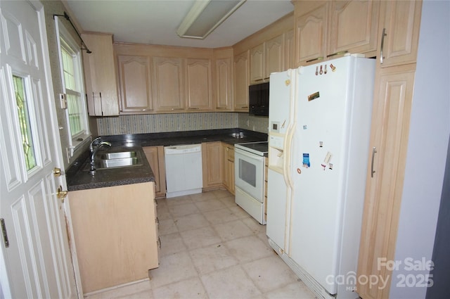 kitchen with dark countertops, a sink, light floors, light brown cabinets, and white appliances