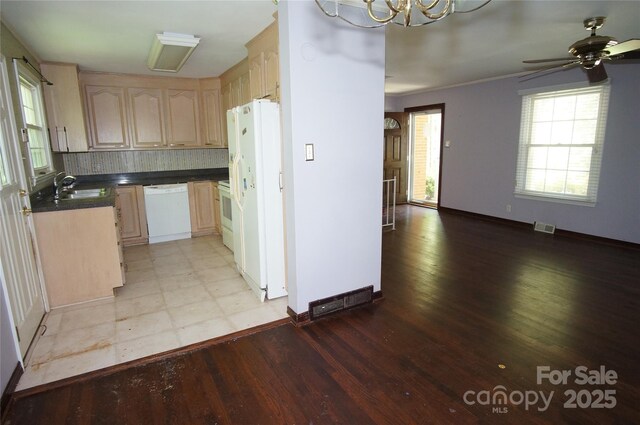 kitchen with visible vents, dark countertops, a sink, white appliances, and light wood-style flooring