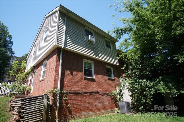 view of home's exterior featuring brick siding, central AC unit, fence, and cooling unit
