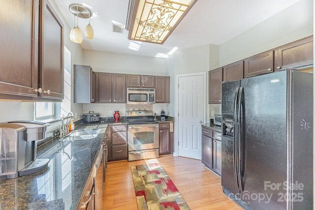 815 Clearbrook Rd, Matthews, NC 28105 - kitchen featuring stainless steel appliances, dark stone countertops, a sink, and light wood-style floors