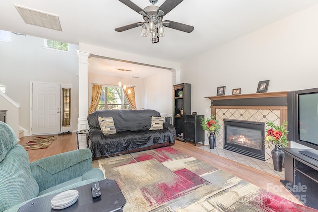 815 Clearbrook Rd, Matthews, NC 28105 - living room with ceiling fan, a tiled fireplace, wood finished floors, ornate columns, and visible vents