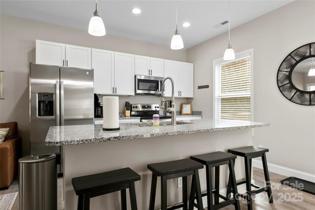 106 Dalton St, Black Mountain, NC 28711 - kitchen featuring appliances with stainless steel finishes, white cabinets, wood finished floors, light stone countertops, and recessed lighting