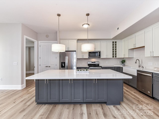 4625 Piedmont Row Dr Unit 410, Charlotte, NC 28210 - kitchen featuring stainless steel appliances, gray cabinetry, a kitchen island, light wood finished floors, and a sink