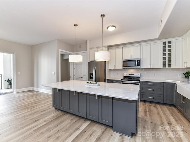 4625 Piedmont Row Dr Unit 410, Charlotte, NC 28210 - kitchen featuring appliances with stainless steel finishes, gray cabinets, a kitchen island, light wood finished floors, and backsplash