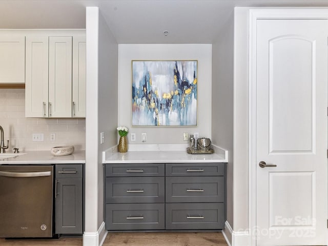 4625 Piedmont Row Dr Unit 410, Charlotte, NC 28210 - bar area featuring dishwasher, light wood-type flooring, backsplash, a sink, and baseboards