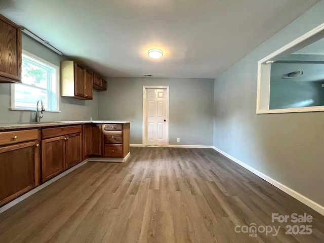 kitchen with light countertops, baseboards, a sink, and wood finished floors