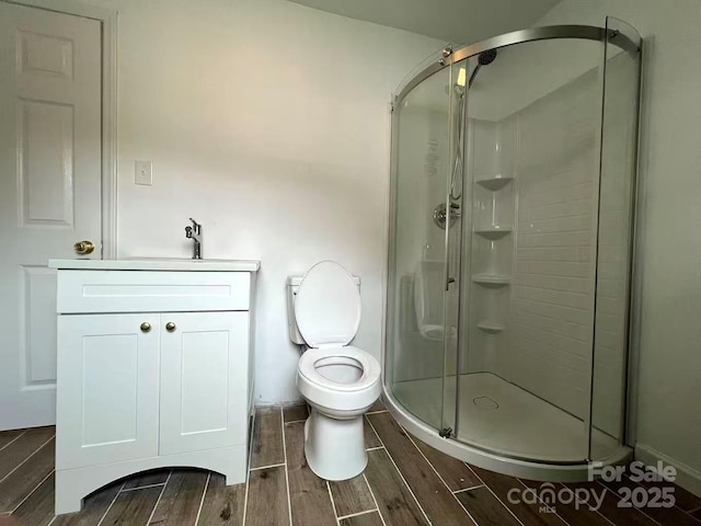 full bathroom featuring vanity, toilet, a shower stall, and wood tiled floor