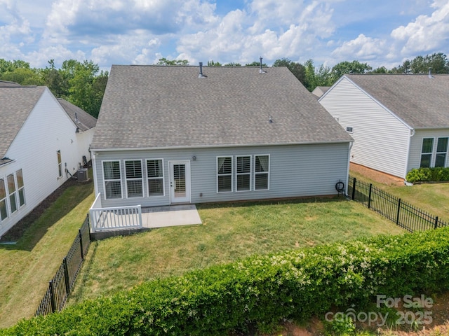 rear view of property featuring a lawn, a fenced backyard, a patio area, and roof with shingles