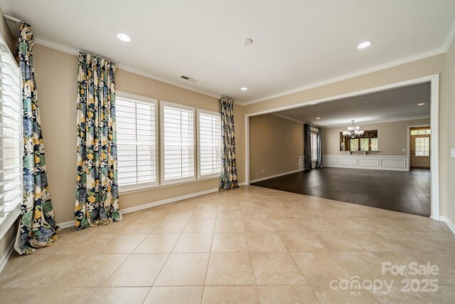 empty room with crown molding, tile patterned floors, a notable chandelier, and plenty of natural light