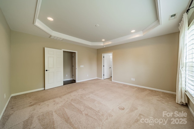 unfurnished bedroom featuring carpet floors, recessed lighting, a tray ceiling, and visible vents