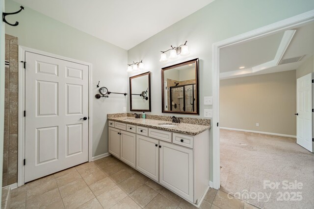 bathroom featuring a sink, baseboards, double vanity, and tiled shower