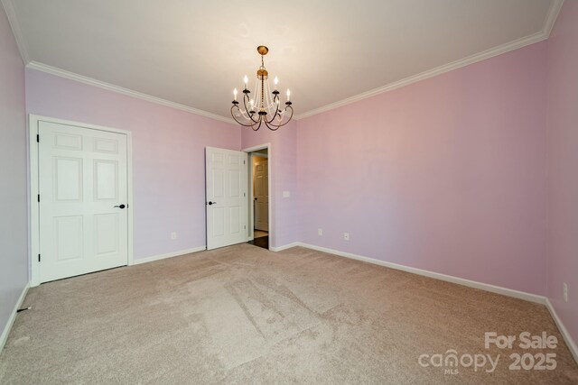 carpeted spare room featuring crown molding, baseboards, and a notable chandelier