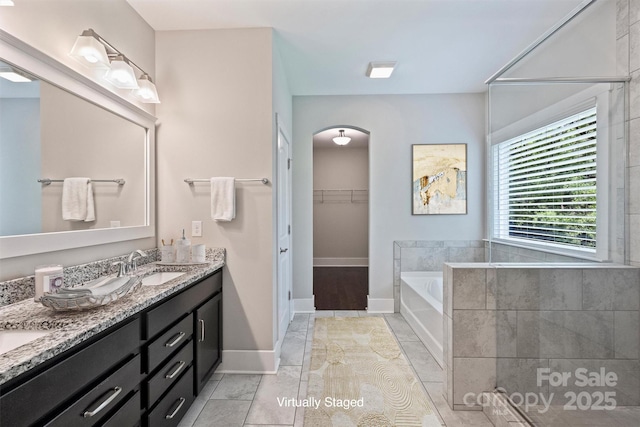 1209 Leigh Ave, Charlotte, NC 28205 - bathroom featuring double vanity, a bath, baseboards, a walk in closet, and marble finish floors