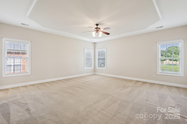 spare room featuring visible vents, ceiling fan, a tray ceiling, and light colored carpet