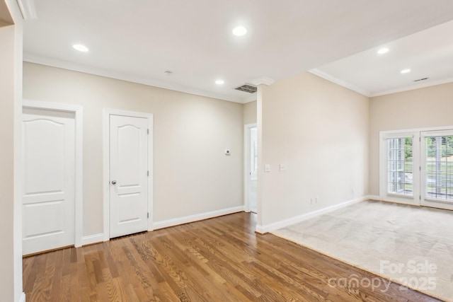 unfurnished room featuring crown molding, baseboards, wood finished floors, and visible vents