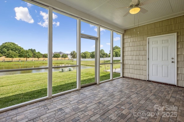 unfurnished sunroom with a ceiling fan and a water view