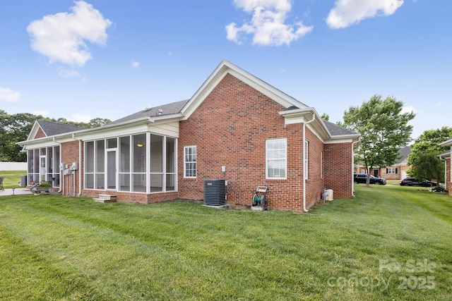 back of house featuring a lawn, cooling unit, a sunroom, and brick siding