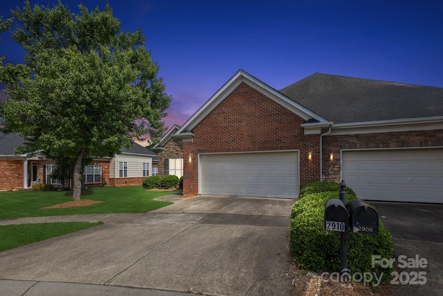 view of property featuring an attached garage, concrete driveway, a front lawn, and brick siding