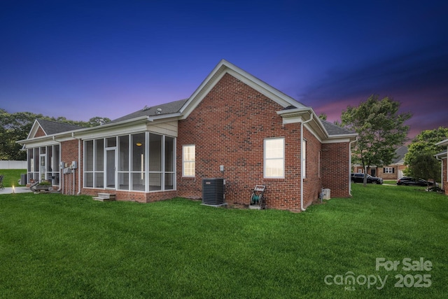 view of side of property with a lawn, brick siding, and a sunroom