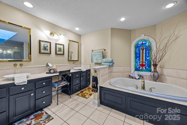 bathroom with double vanity, a textured ceiling, a sink, and a garden tub