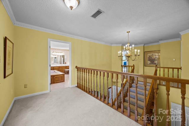 corridor with visible vents, baseboards, an upstairs landing, an inviting chandelier, and carpet