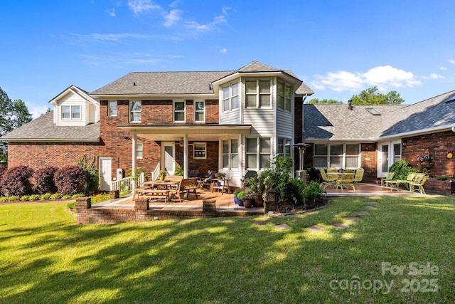 rear view of property featuring a patio, a lawn, and brick siding
