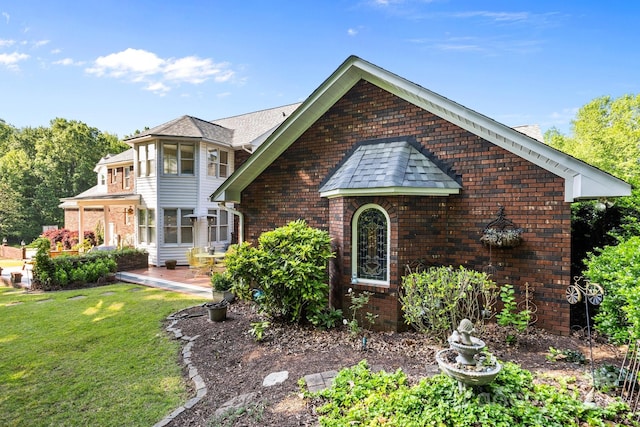 view of front of home featuring a patio area, a front lawn, and brick siding