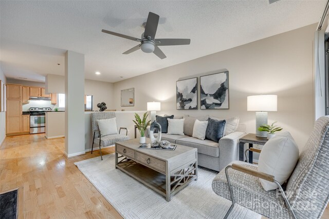 living area featuring light wood-style floors, a ceiling fan, and baseboards