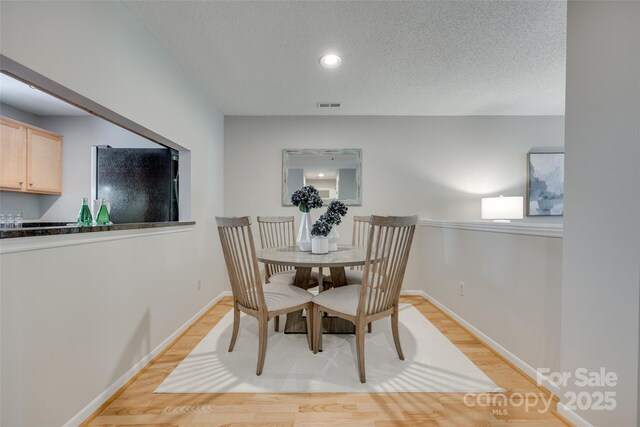dining room featuring light wood-type flooring, baseboards, recessed lighting, and a textured ceiling