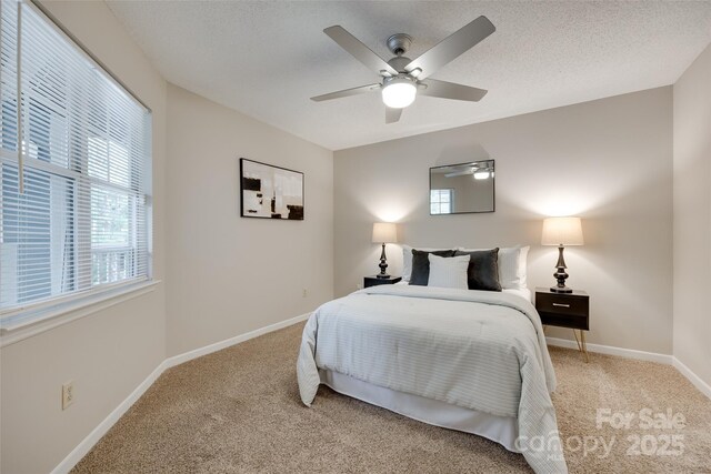 bedroom with carpet floors, baseboards, ceiling fan, and a textured ceiling