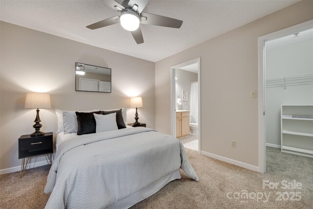 bedroom with light colored carpet, a spacious closet, a closet, baseboards, and a textured ceiling