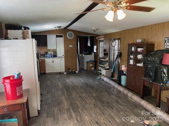 interior space with wood walls, dark wood-style flooring, a ceiling fan, and lofted ceiling