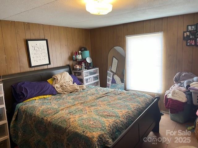 bedroom featuring wood walls and multiple windows