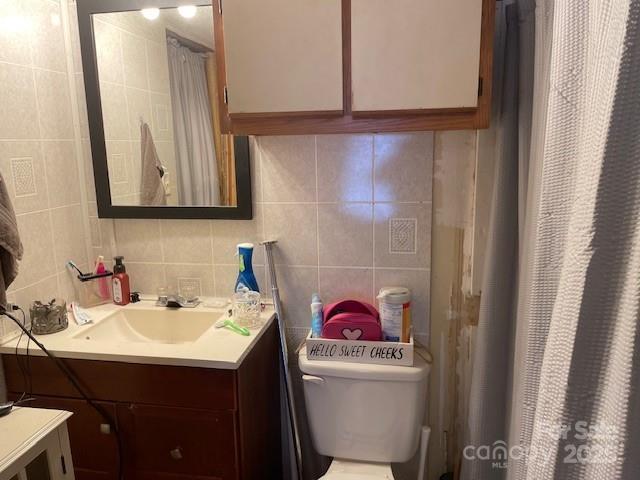bathroom featuring tile walls, decorative backsplash, vanity, and toilet