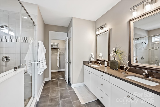 bathroom featuring a sink, a shower stall, double vanity, and a spacious closet