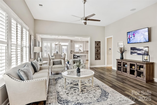 living room with baseboards, dark wood-style flooring, and ceiling fan with notable chandelier