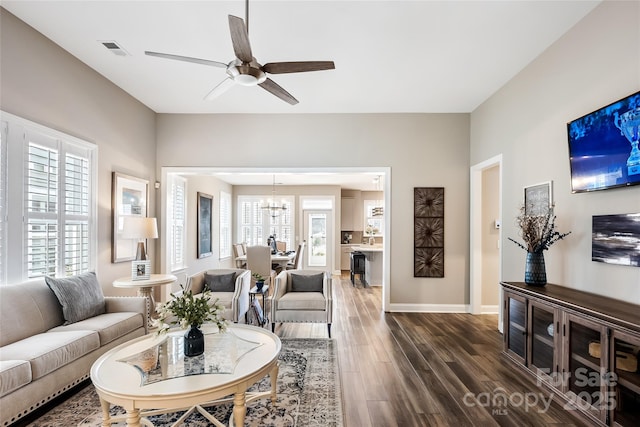 living room with visible vents, dark wood-style floors, a healthy amount of sunlight, and ceiling fan with notable chandelier