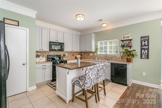 kitchen featuring decorative backsplash, ornamental molding, black appliances, and visible vents