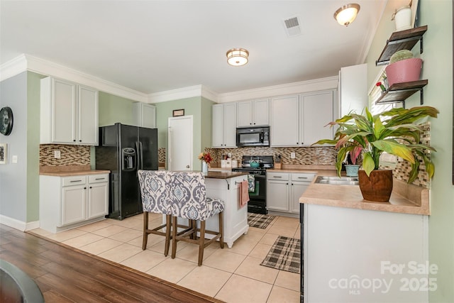 kitchen with visible vents, ornamental molding, a center island, backsplash, and black appliances