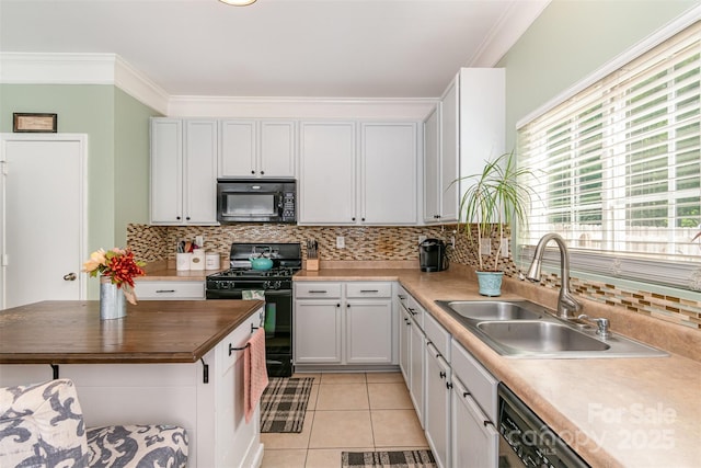 kitchen featuring wooden counters, tasteful backsplash, a sink, light tile patterned floors, and black appliances