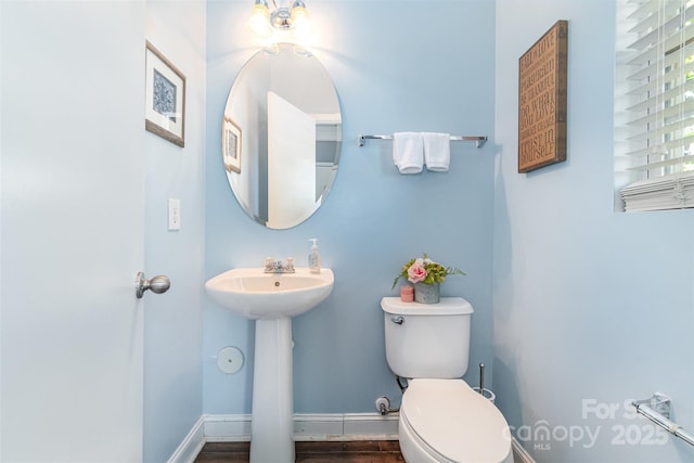half bathroom featuring a sink, baseboards, and toilet