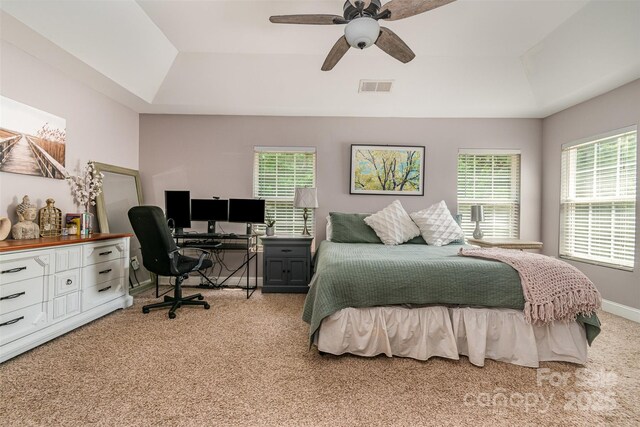 bedroom with a ceiling fan, visible vents, baseboards, light carpet, and a tray ceiling