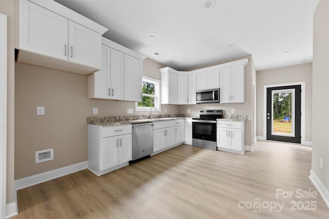 213 Benfield Rd, Kings Mountain, NC 28086 - kitchen with stainless steel appliances, light wood finished floors, white cabinetry, and light stone countertops