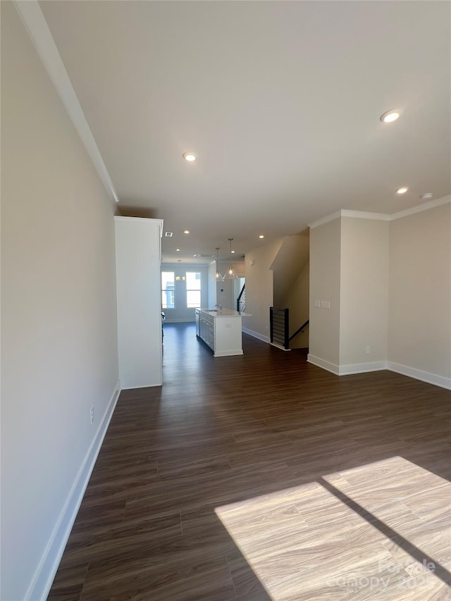 unfurnished living room featuring recessed lighting, baseboards, ornamental molding, and dark wood finished floors
