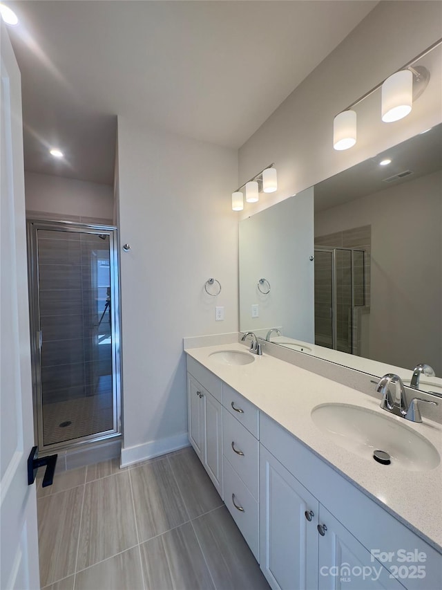 bathroom featuring a shower stall, double vanity, baseboards, and recessed lighting