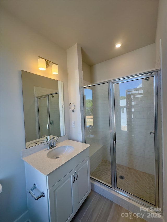bathroom featuring a stall shower, vanity, recessed lighting, and wood finished floors