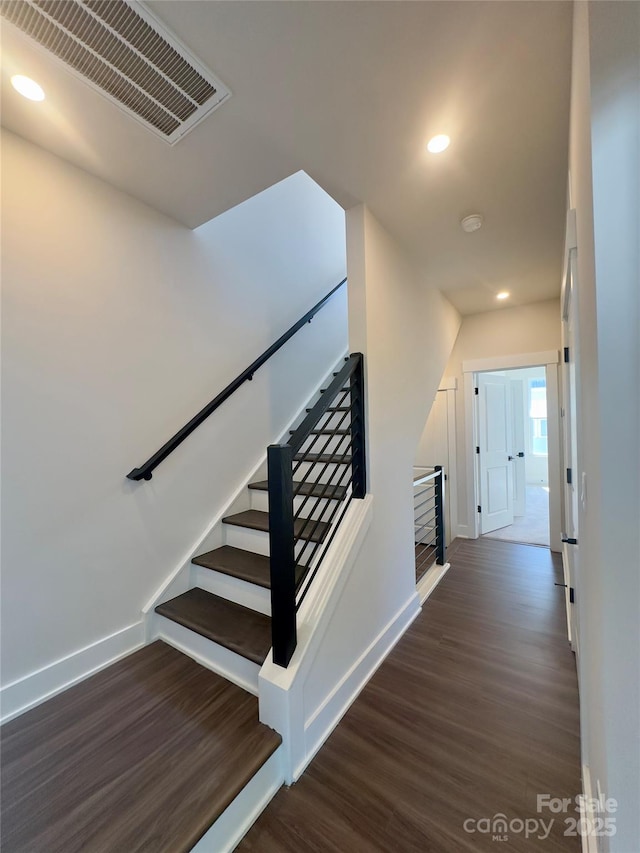 staircase featuring wood finished floors, baseboards, and recessed lighting