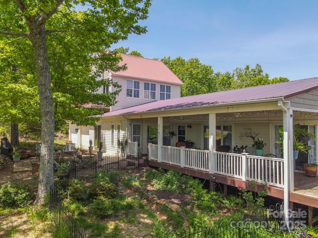 exterior space with fence, covered porch, and metal roof